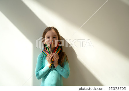 Adorable little girl holding colorful pencils and smiling Adorable little girl holding colorful pencils and smiling 65378705