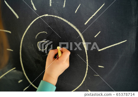 Child drawing sun on chalkboard at home 65378714
