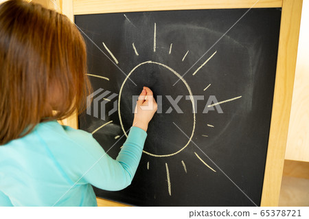 Little girl drawing sun on chalkboard at home Little girl drawing sun on chalkboard at home 65378721