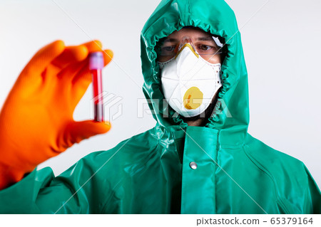 Person in protective impermeable suit looking at the blood sample Person in protective impermeable suit looking at the blood sample 65379164