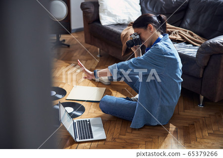 Nice woman in denim suit using old camera indoors 65379266