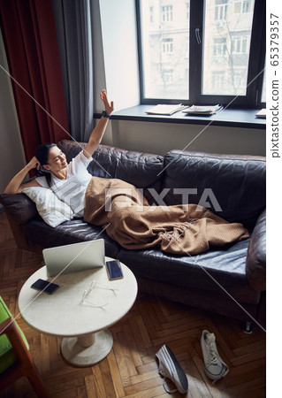 Relaxed girl stretching herself in her cozy apartment 65379357