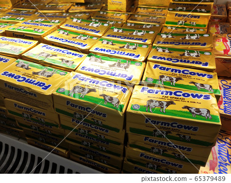 Butter in square packaging is on display in chiller shelves inside the supermarket. Butter is a dairy product made from the fat and protein components of milk or cream.  65379489