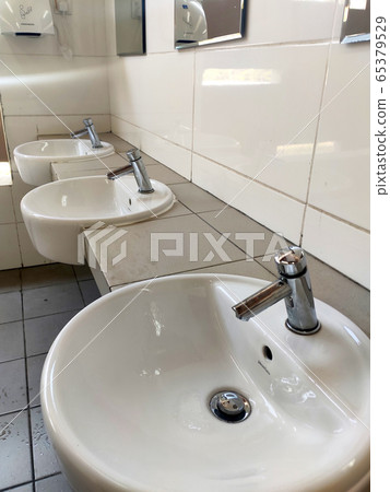 SEREMBAN, MALAYSIA -APRIL 1, 2020: Hand washbasins at the public toilet. Installation complete with face mirror. Made from white glazed ceramic. 65379529