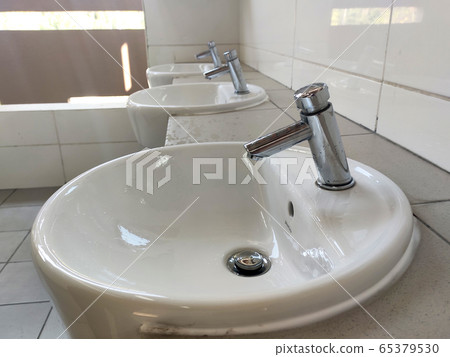 SEREMBAN, MALAYSIA -APRIL 1, 2020: Hand washbasins at the public toilet. Installation complete with face mirror. Made from white glazed ceramic. 65379530