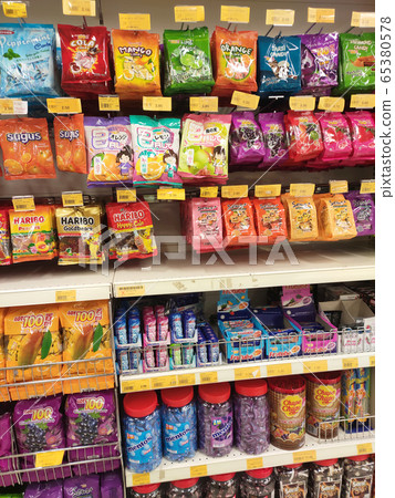 The candies are wrapped in commercial plastic packaging and labelled by brand. Display on a supermarket shelf for sale. Every item has a different price tag. The candies are wrapped in commercial plastic packaging and labelled by brand. Display on a supermarket shelf for sale. Every item has a different price tag. 65380578
