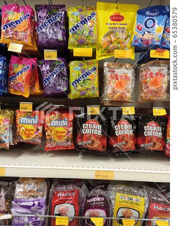 The candies are wrapped in commercial plastic packaging and labelled by brand. Display on a supermarket shelf for sale. Every item has a different price tag. The candies are wrapped in commercial plastic packaging and labelled by brand. Display on a supermarket shelf for sale. Every item has a different price tag. 65380579