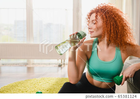 Sporty girl drink water and hold dumpbell Sporty girl drink water and hold dumpbell 65381124