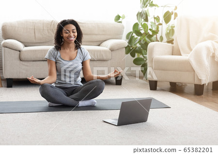Happy African American Woman Meditating In Front Of Laptop At Home Happy African American Woman Meditating In Front Of Laptop At Home 65382201