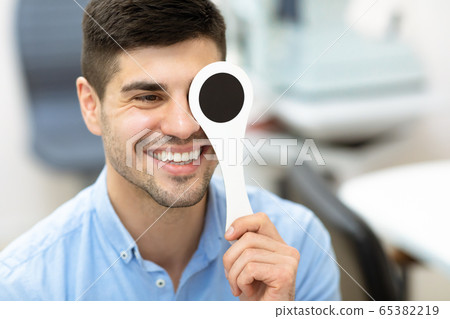 Patient and optician doing eye test in clinic 65382219