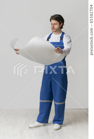 Full-length portrait of young construction engineer checking draft or building plan Full-length portrait of young construction engineer checking draft or building plan 65382704