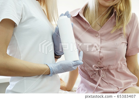 Doctor shows the patient remedy in beauty salon. Cosmetology Doctor shows the patient remedy in beauty salon. Cosmetology 65383407