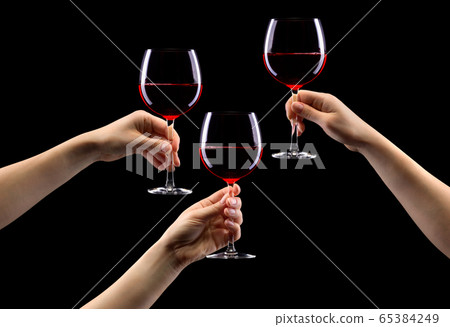 Set of hands holding red wine glass isolated on black. 65384249