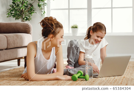 Cheerful woman with daughter using laptop during 65384304