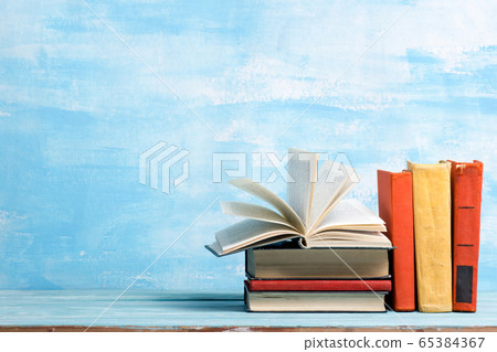 Composition with vintage old hardback books, diary, fanned pages on wooden deck table and abstract background. Books stacking. Back to school. Copy Space. Education background. 65384367