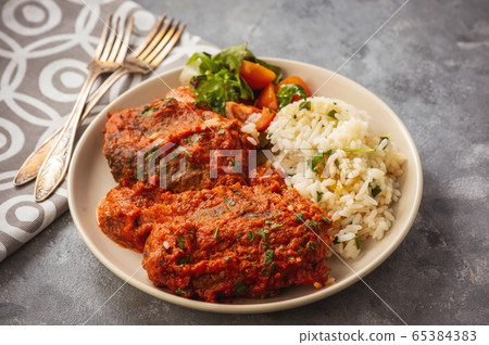 Minced meat cutlets in tomato sauce, served with rice, bifteki-greek cuisine. 65384383
