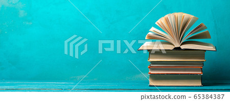 Composition with vintage old hardback books, diary, fanned pages on wooden deck table and abstract background. Books stacking. Back to school. Copy Space. Education background. 65384387