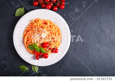 Spaghetti with tomato sauce and cherry tomatoes with basil on a dark background Spaghetti with tomato sauce and cherry tomatoes with basil on a dark background 65385791