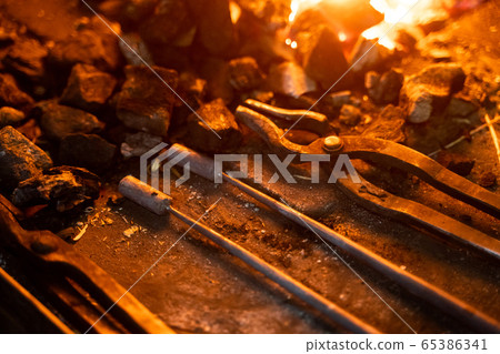 Grungy tools inside furnace in smithy from above 65386341