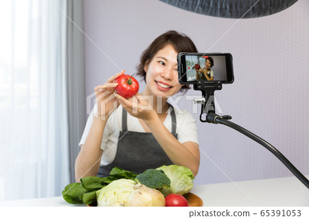 A woman shooting a video with a smartphone A woman shooting a video with a smartphone 65391053