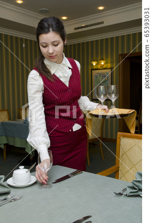 Young beautiful waitress serving the table in the restaurant Young beautiful waitress serving the table in the restaurant 65393031