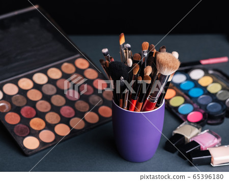 set of professional makeup brushes on the background of a palette with colored eye shadows and cosmetics set of professional makeup brushes on the background of a palette with colored eye shadows and cosmetics 65396180