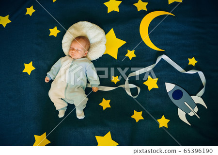 baby boy lying asleep in the suit of an astronaut 65396190