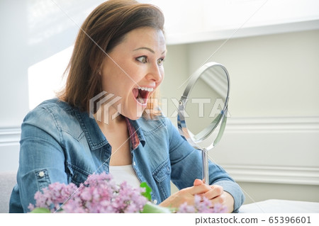 Mature woman looking in the mirror and screaming Mature woman looking in the mirror and screaming 65396601