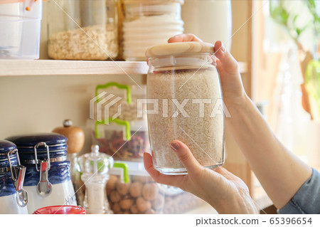 Food products in the kitchen. Woman taking jar of rice Food products in the kitchen. Woman taking jar of rice 65396654