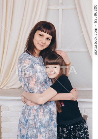 Warming and relaxing near fireplace. Mother and daughter hugging. Concept of family , motherhood, interior, home, childhood, mother's day, children's day 65396800