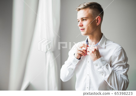 Grooms morning preparation. Handsome man getting dressed and preparing for the wedding Grooms morning preparation. Handsome man getting dressed and preparing for the wedding 65398223