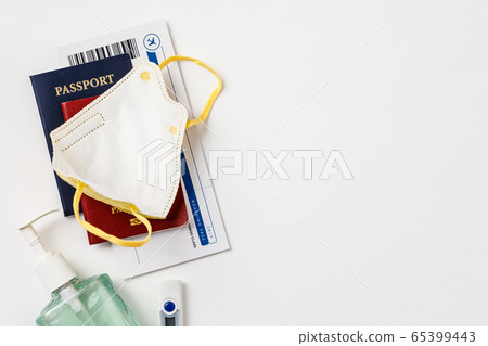 Coronavirus and travel concept. Passports, airplane tickets, sanitizer, thermometer and medical mask flat lay 65399443
