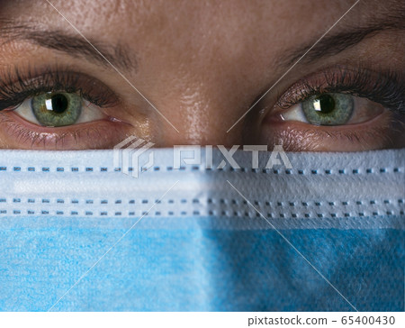 Tired doctor in mask looks at camera. Close up. Selective focus Tired doctor in mask looks at camera. Close up. Selective focus 65400430