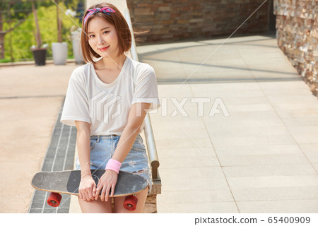 Pretty teenage woman riding a skateboard 65400909