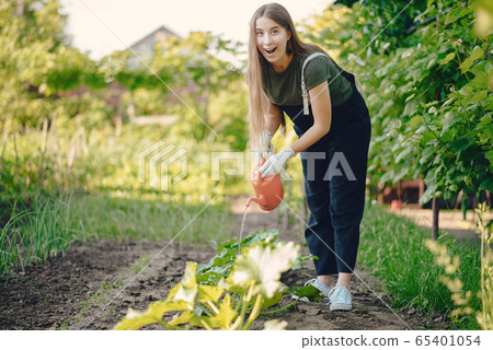 Beautiful woman works in a garden near the house Beautiful woman works in a garden near the house 65401054