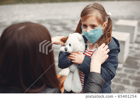 Woman in a disposable mask is teaching her child to wear a respirator 65401254