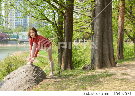 Pretty 20s woman stretching in the park 65402571