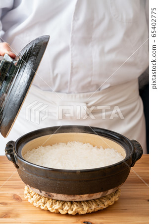 Freshly cooked rice in front of the plate that opens the lid of the clay pot 65402775