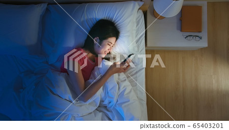 woman use smartphone on bed 65403201