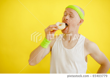 bald funny man with a donut on a yellow background. funny fitness. retro style bald funny man with a donut on a yellow background. funny fitness. retro style 65403779
