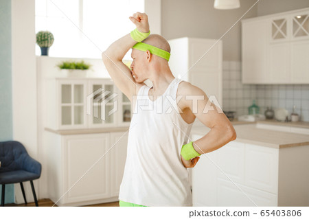funny bald man in the kitchen in sportswear showing muscles. retro style funny bald man in the kitchen in sportswear showing muscles. retro style 65403806