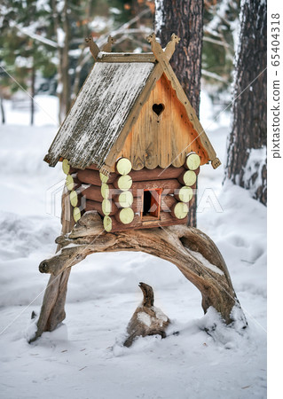 Wooden birdhouse. Log cabin birdhouse mounted on snag tree in snowy forest Wooden birdhouse. Log cabin birdhouse mounted on snag tree in snowy forest 65404318