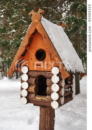 Wooden birdhouse. Log cabin birdhouse in snowy forest 65404324
