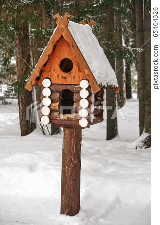 Wooden birdhouse. Log cabin birdhouse in snowy forest 65404326