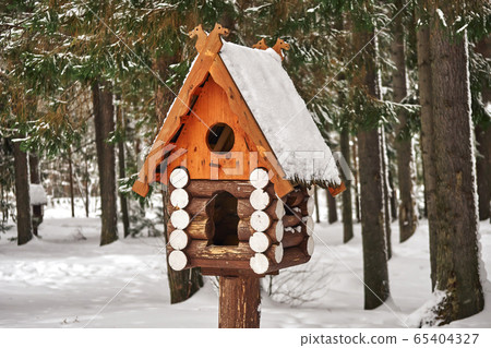Wooden birdhouse. Log cabin birdhouse in snowy forest 65404327