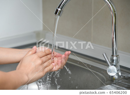 Woman washing hands in a sink with tap water 65406200