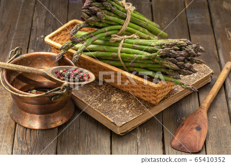 Bunch of fresh green asparagus spears in basket on a rustic wooden table. 65410352