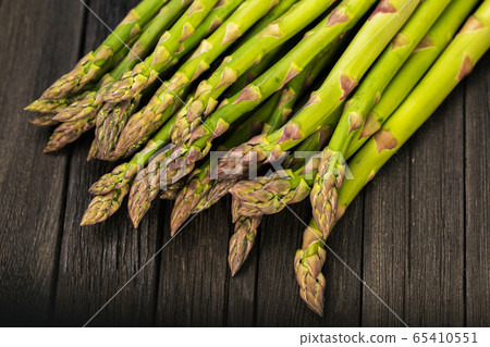 Bunch of fresh green asparagus spears on a rustic wooden table 65410551