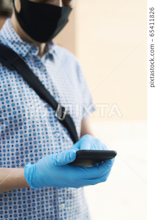man wearing latex gloves using his smartphone 65411826