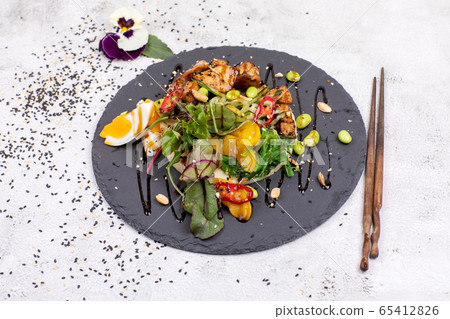Poke bowl with chicken and vegetables on the white table. 65412826